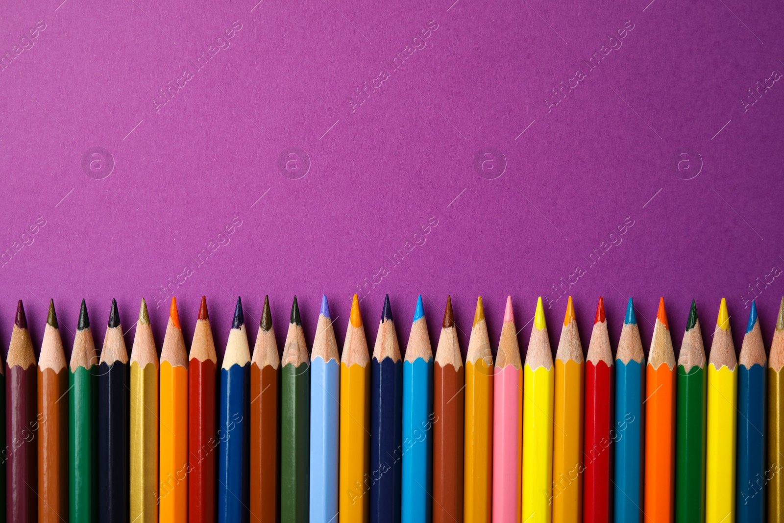Photo of Flat lay composition with color pencils on purple background. Space for text