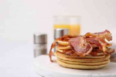 Photo of Delicious pancakes with bacon and honey on white table, closeup. Space for text