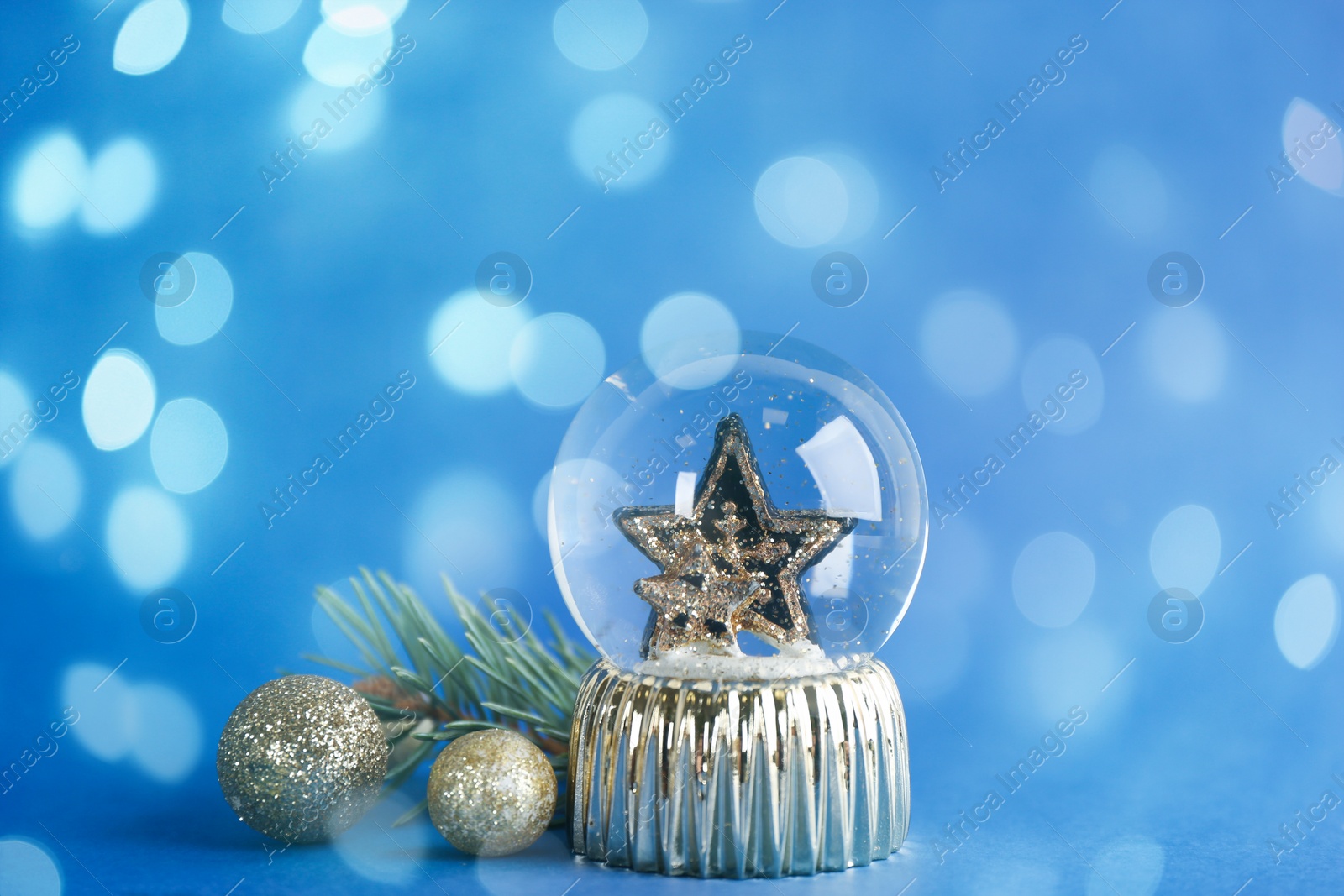 Image of Beautiful Christmas snow globe and decor on blue background, bokeh effect