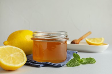 Photo of Sweet honey and fresh lemons on white table, space for text