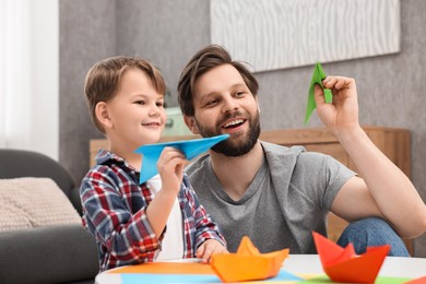 Photo of Happy dad and son playing with paper planes at home