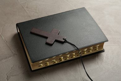 Photo of Wooden Christian cross and Bible on grey table