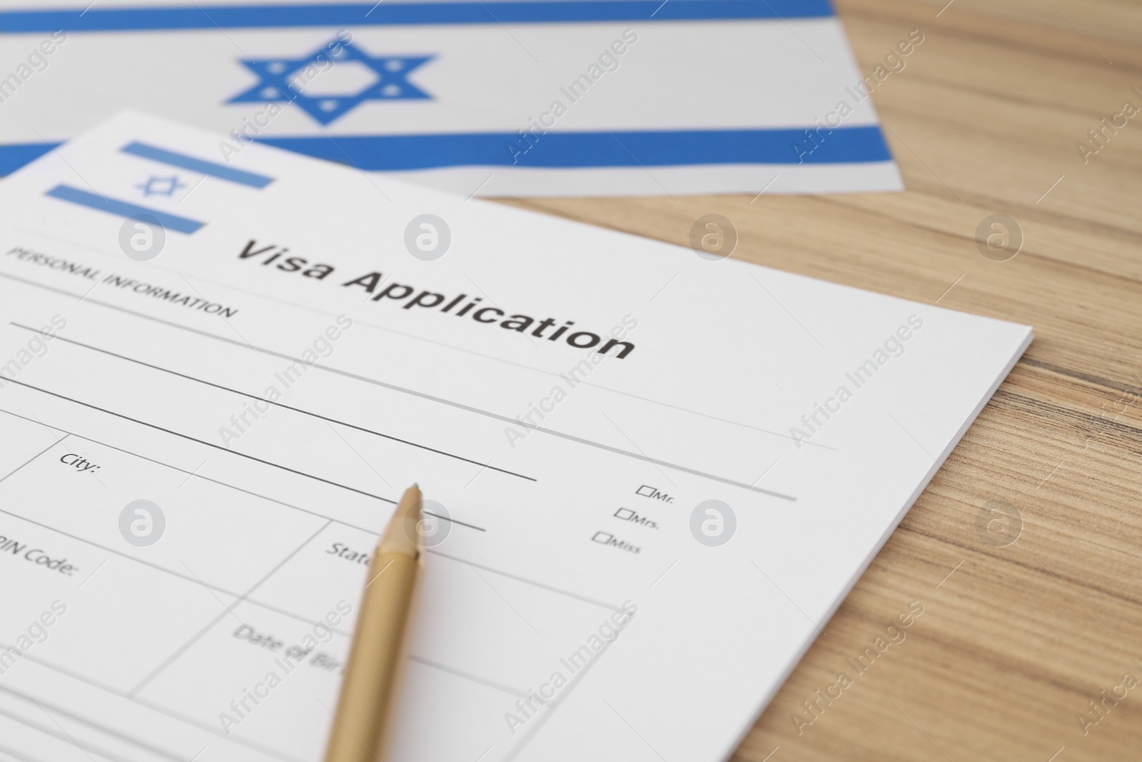 Photo of Immigration to Israel. Visa application form, pencil and flag on wooden table, closeup