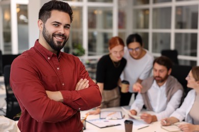 Photo of Team of employees working together in office. Happy man indoors