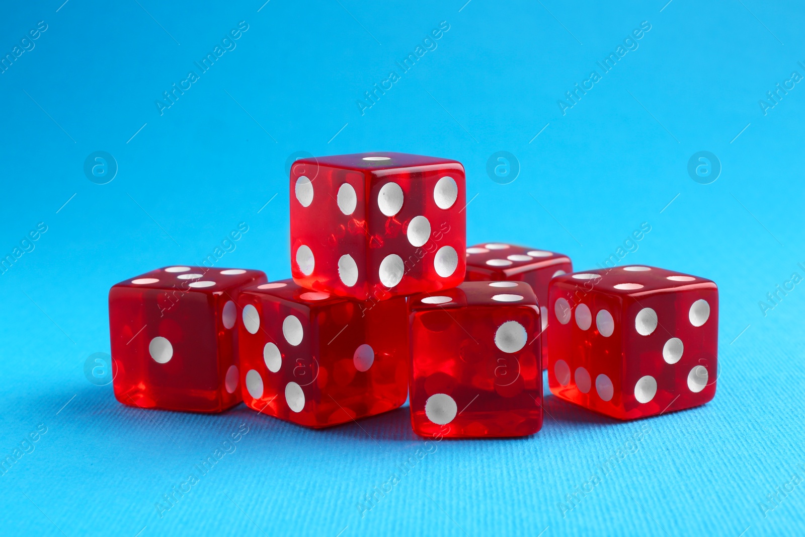 Photo of Many red game dices on light blue background, closeup