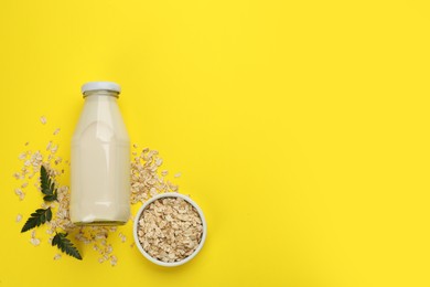 Photo of Vegan milk and oat flakes on yellow background, flat lay. Space for text