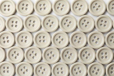 Photo of Many grey sewing buttons on white background, closeup