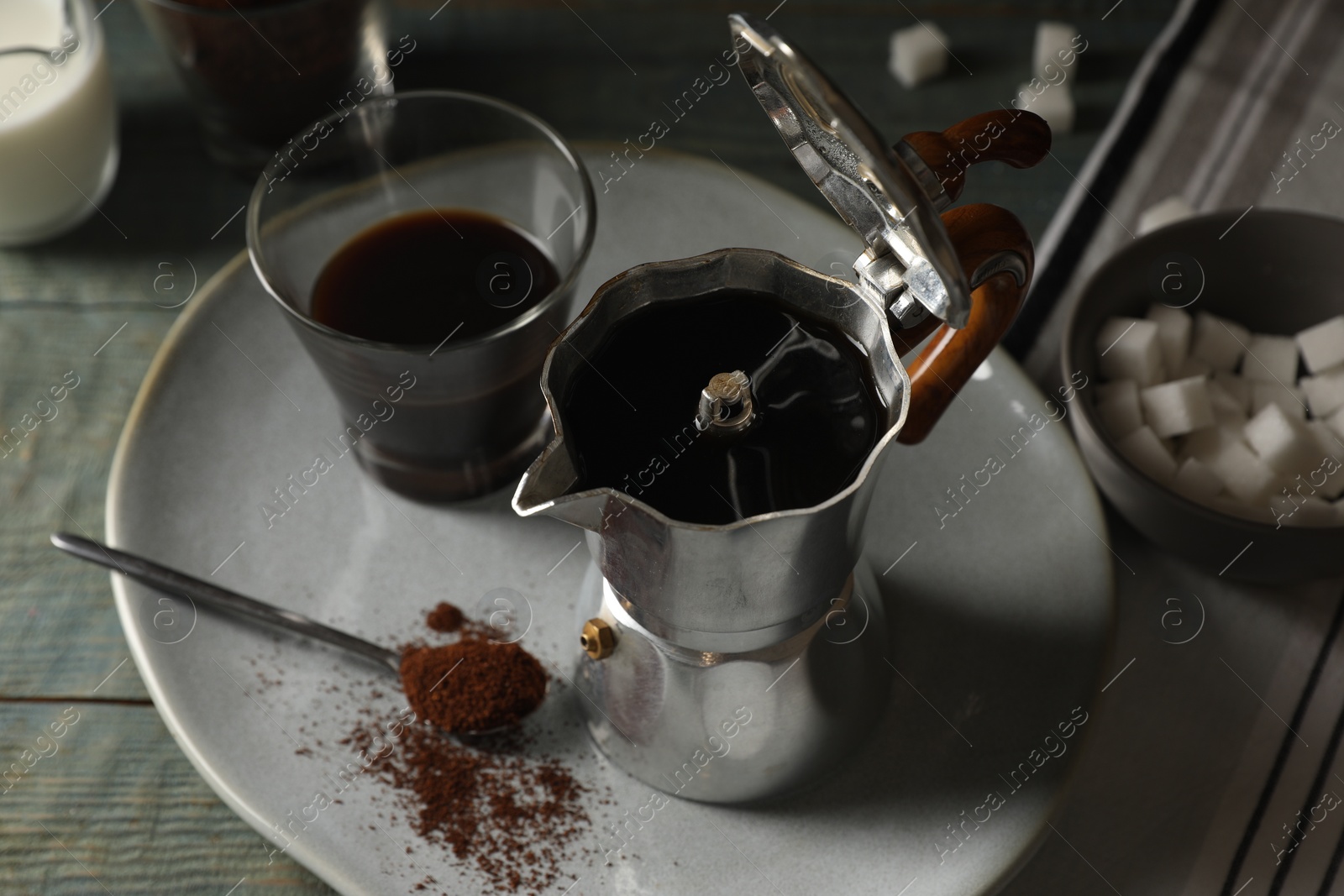 Photo of Brewed coffee in moka pot and glass on rustic wooden table, closeup