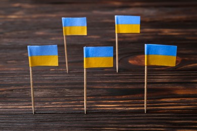 Photo of Small paper flags of Ukraine on wooden table