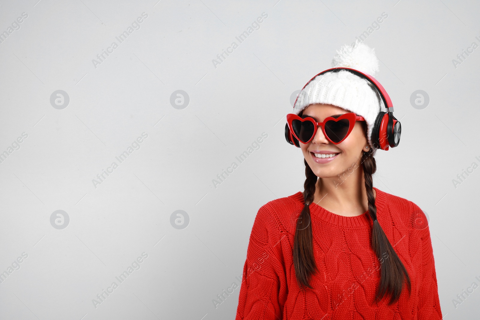 Photo of Young woman listening to music with headphones on grey background, space for text