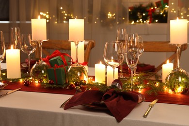 Photo of Christmas table setting with burning candles and festive decor