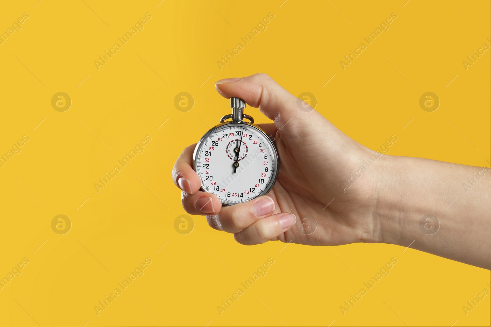 Photo of Woman holding vintage timer on yellow background, closeup