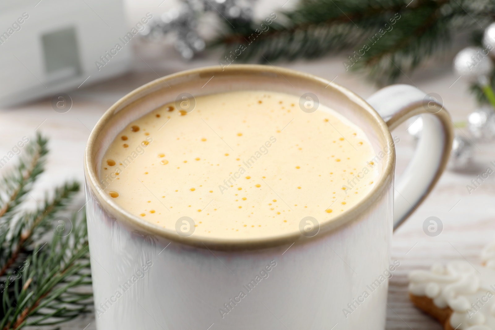 Photo of Cup of delicious eggnog on table, closeup