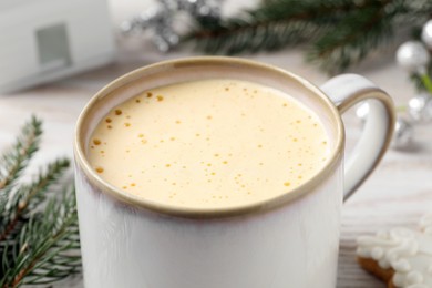 Cup of delicious eggnog on table, closeup