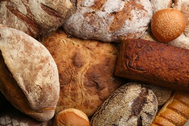 Different kinds of delicious bread as background, top view
