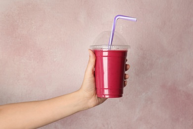 Woman holding plastic cup with delicious smoothie on color background