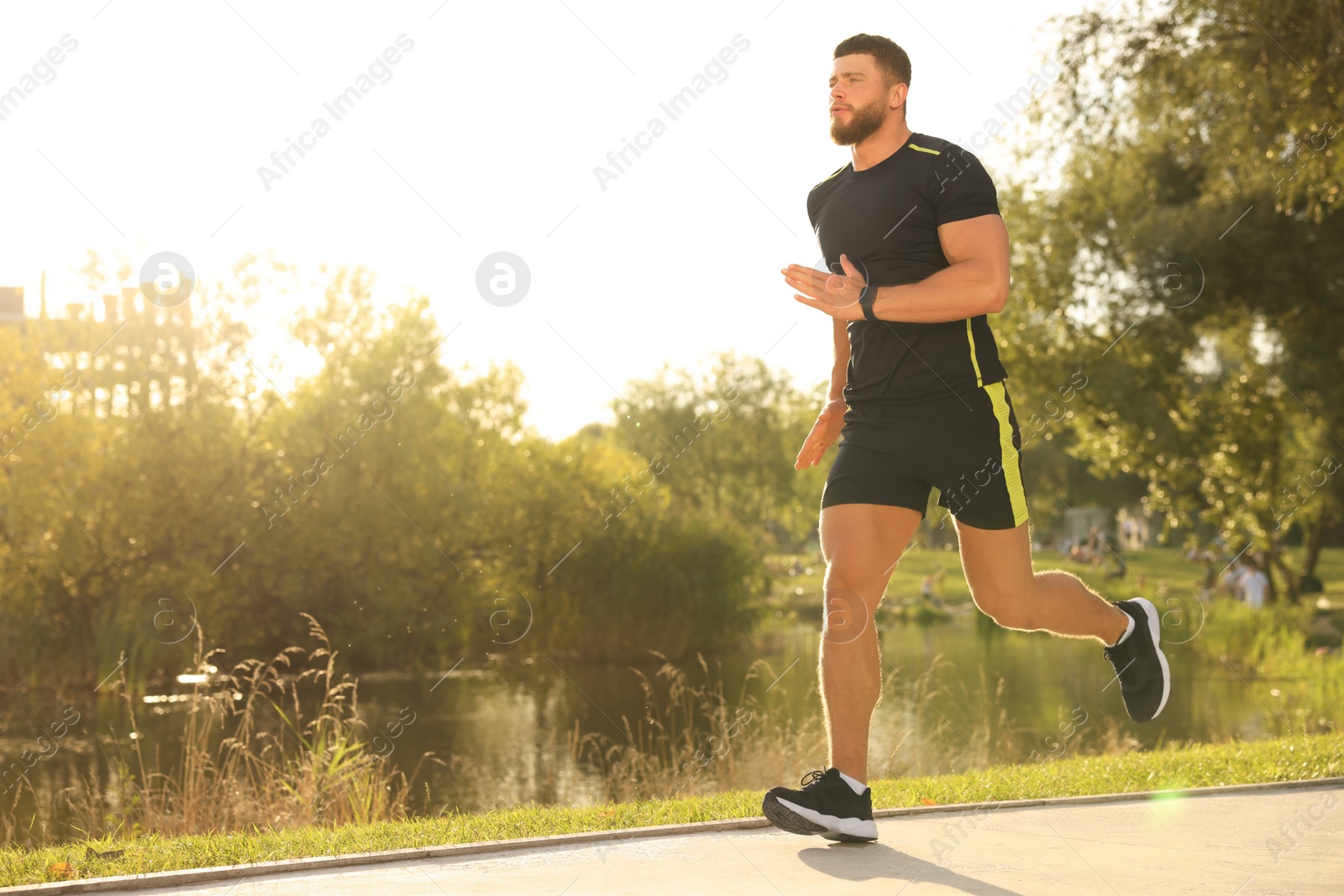 Photo of Young man running near pond in park. Space for text