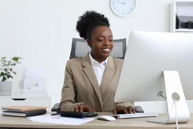 Professional accountant working on computer at wooden desk in office