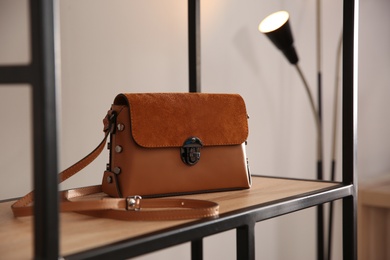 Photo of Elegant brown bag on shelf in luxury boutique
