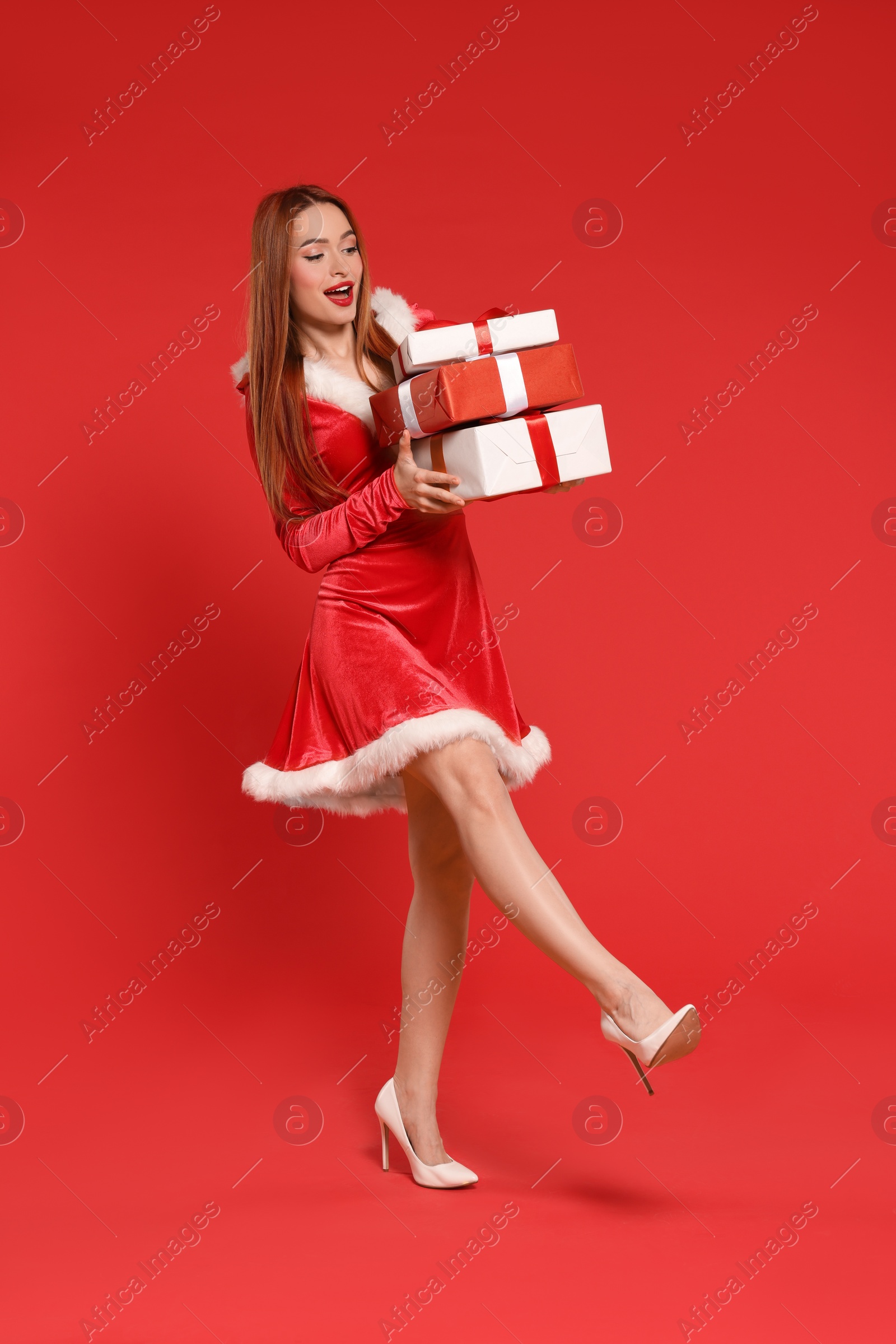 Photo of Young woman with Christmas gifts on red background