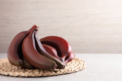 Delicious red baby bananas on light table, space for text