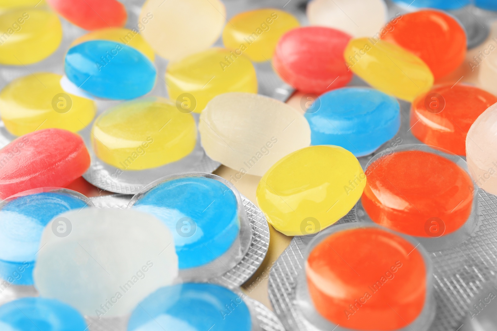 Photo of Blisters and many colorful cough drops as background, closeup