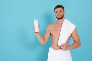 Photo of Shirtless young man holding bottle of shampoo on light blue background, space for text