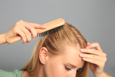 Photo of Woman with hair loss problem on grey background, closeup. Trichology treatment