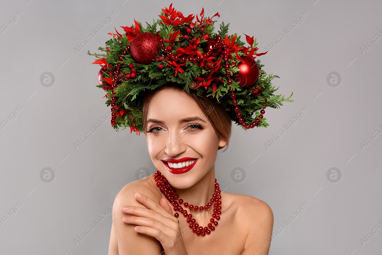 Photo of Beautiful young woman wearing Christmas wreath on grey background