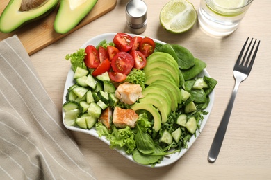 Photo of Delicious avocado salad with fried chicken on wooden table, flat lay