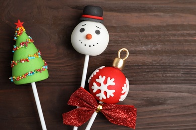 Delicious Christmas themed cake pops on wooden table, flat lay