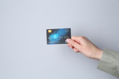 Photo of Woman holding credit card on light grey background, closeup