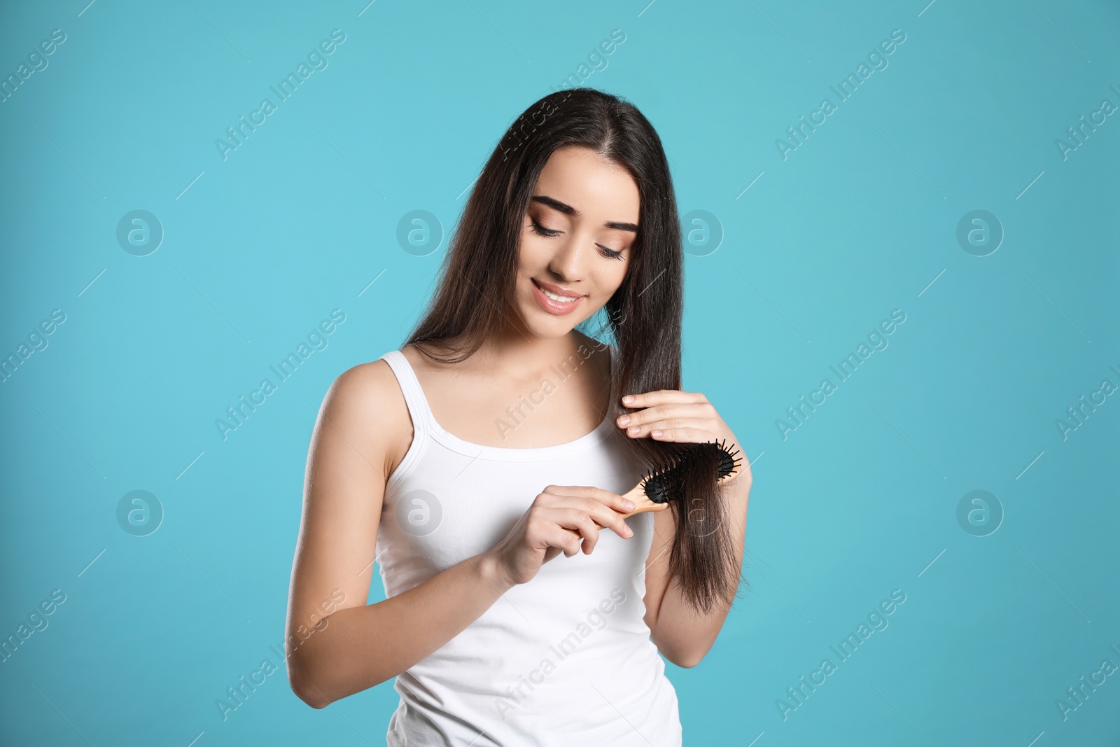 Photo of Beautiful young woman with hair brush on color background