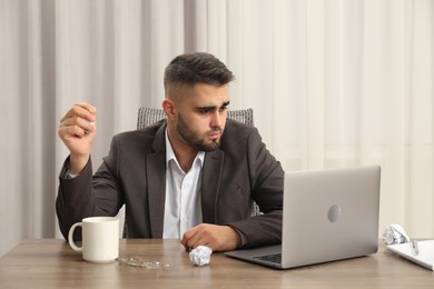 Sad businessman sitting at table in office