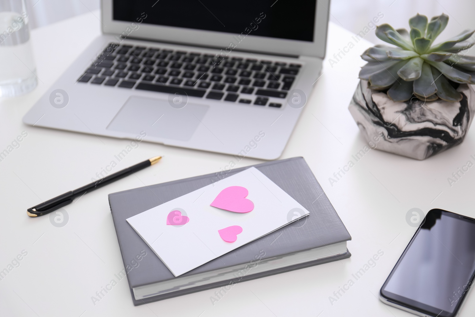 Photo of Greeting card with hearts at workplace. Valentine's Day celebration