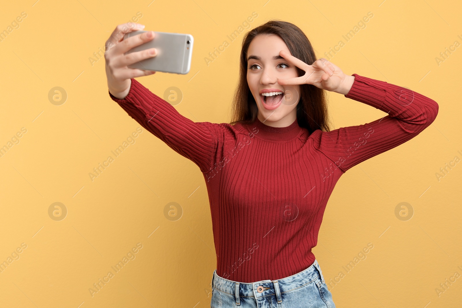 Photo of Attractive young woman taking selfie with phone on color background