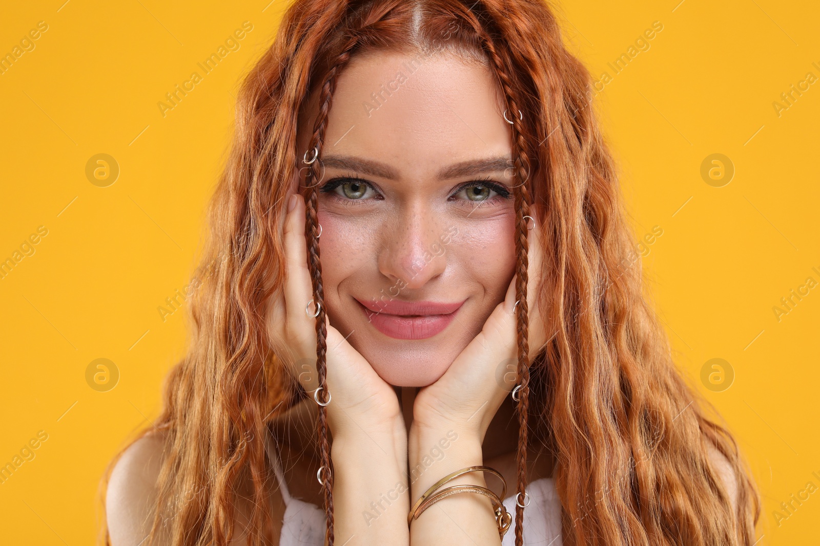 Photo of Beautiful young hippie woman on orange background, closeup