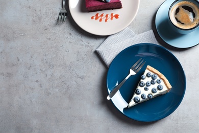 Photo of Flat lay composition with piece of tasty blueberry cake and space for text on gray table