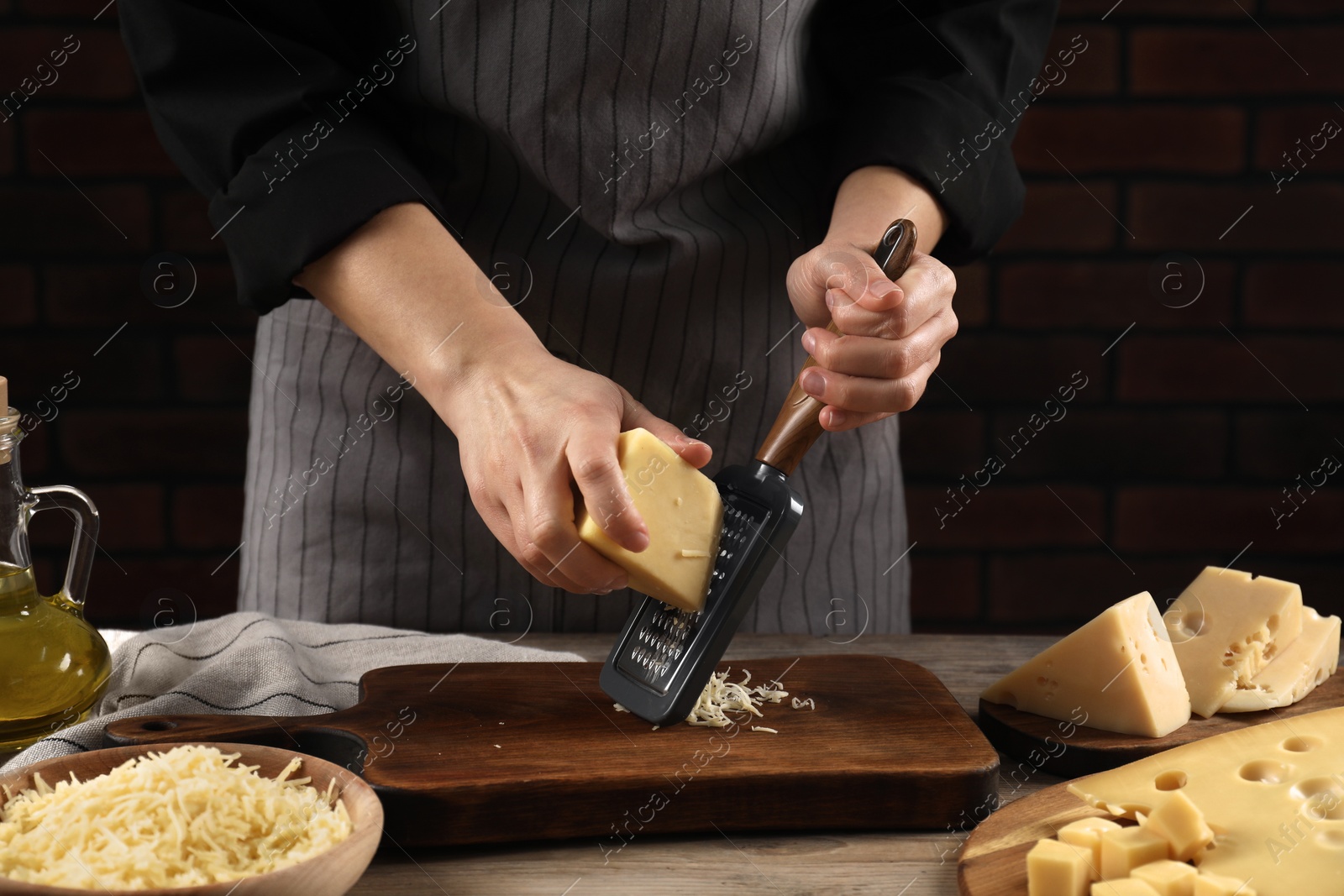 Photo of Woman grating cheese at wooden table, closeup