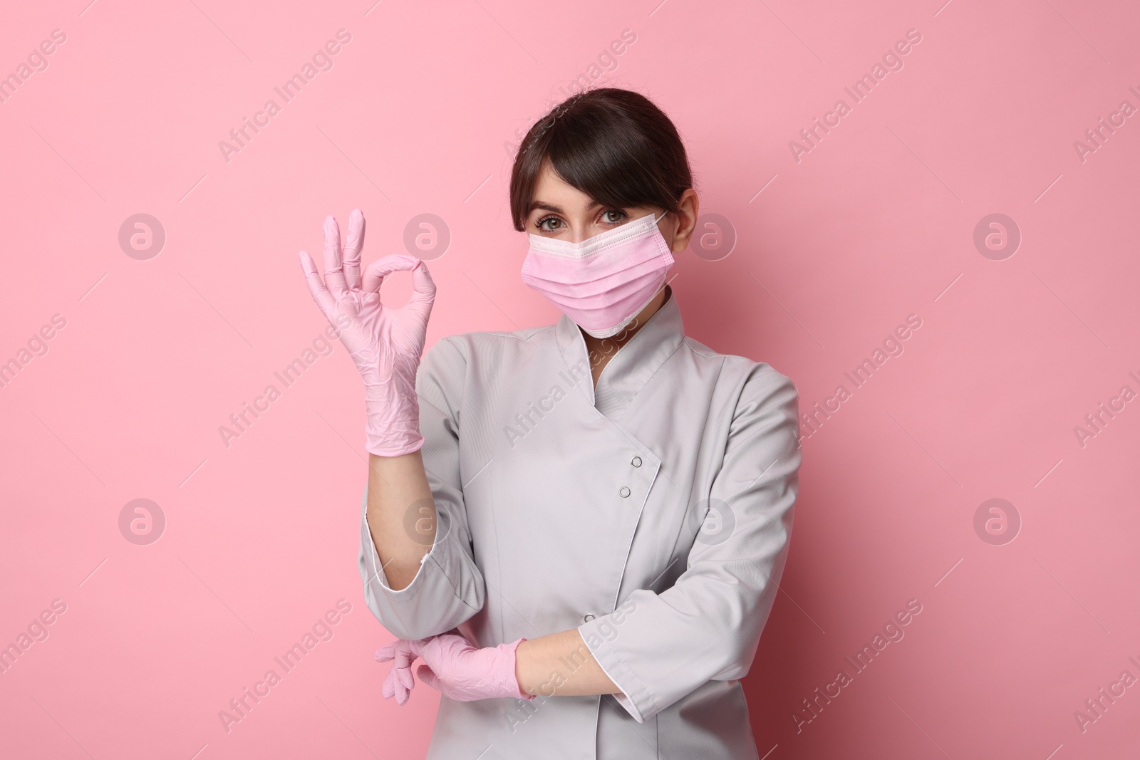 Photo of Cosmetologist showing OK gesture on pink background