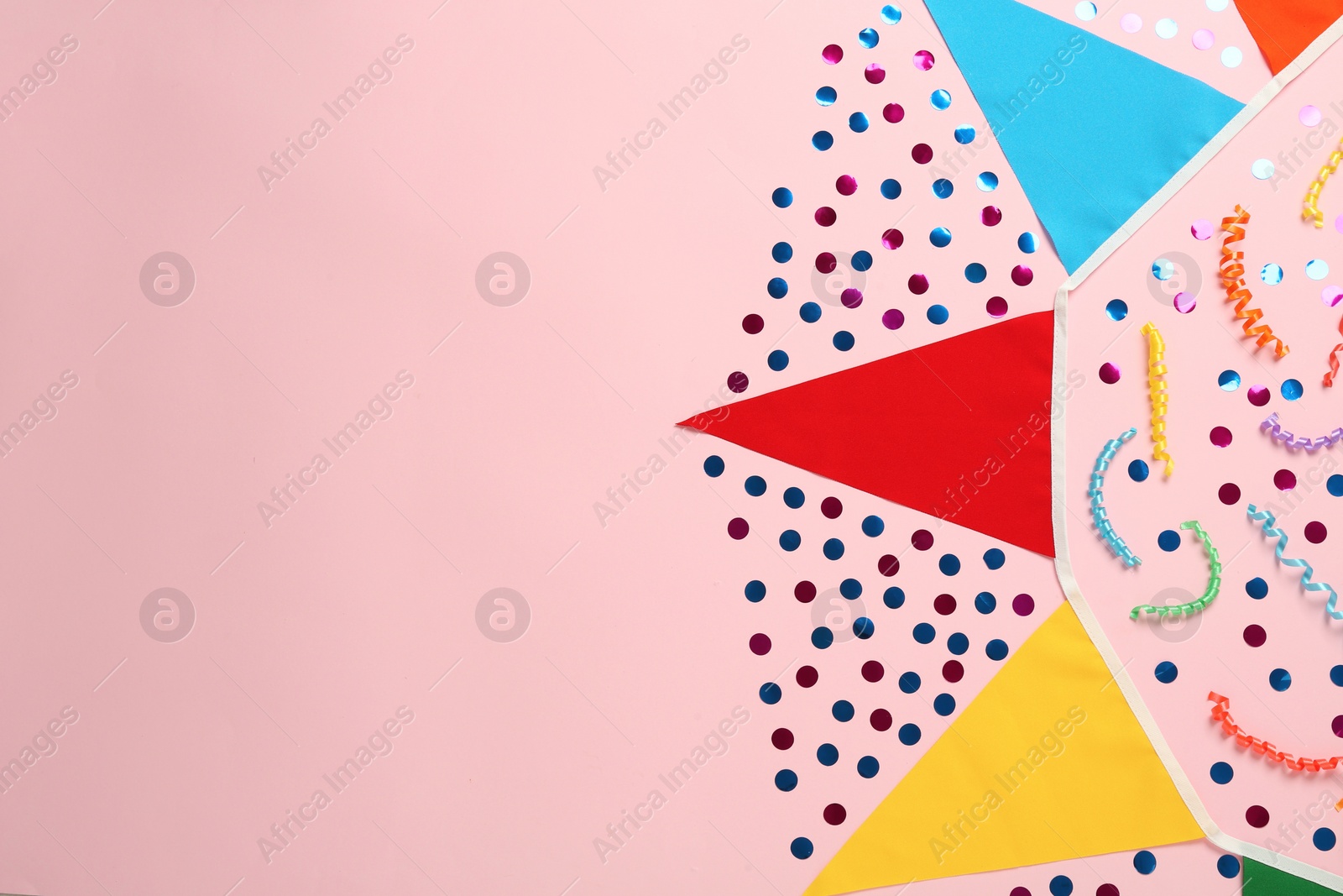 Photo of Bunting with colorful triangular flags and other festive decor on pink background, flat lay. Space for text