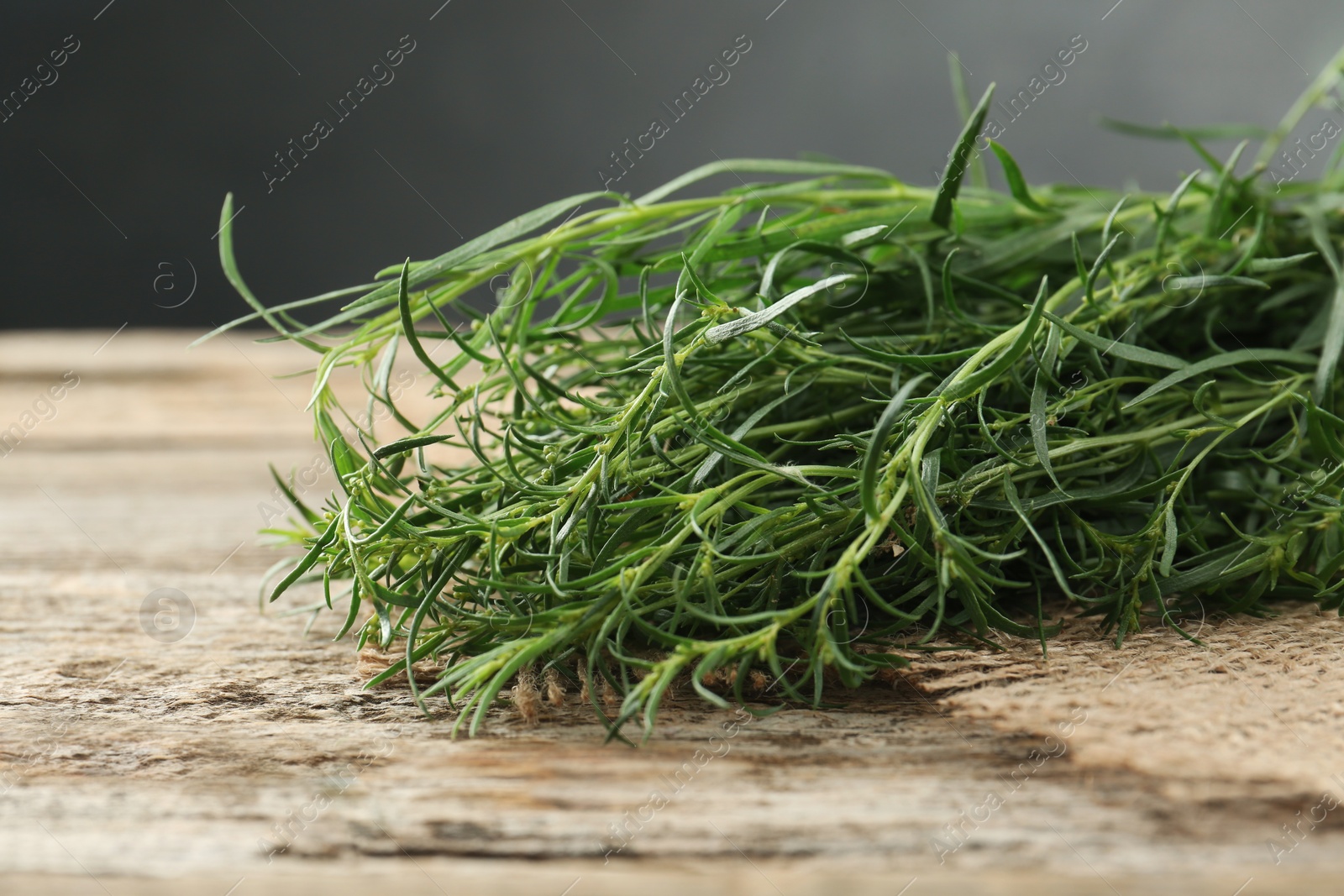 Photo of Bunch of fresh tarragon sprigs on wooden table, closeup