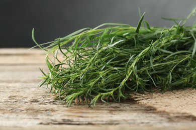 Bunch of fresh tarragon sprigs on wooden table, closeup