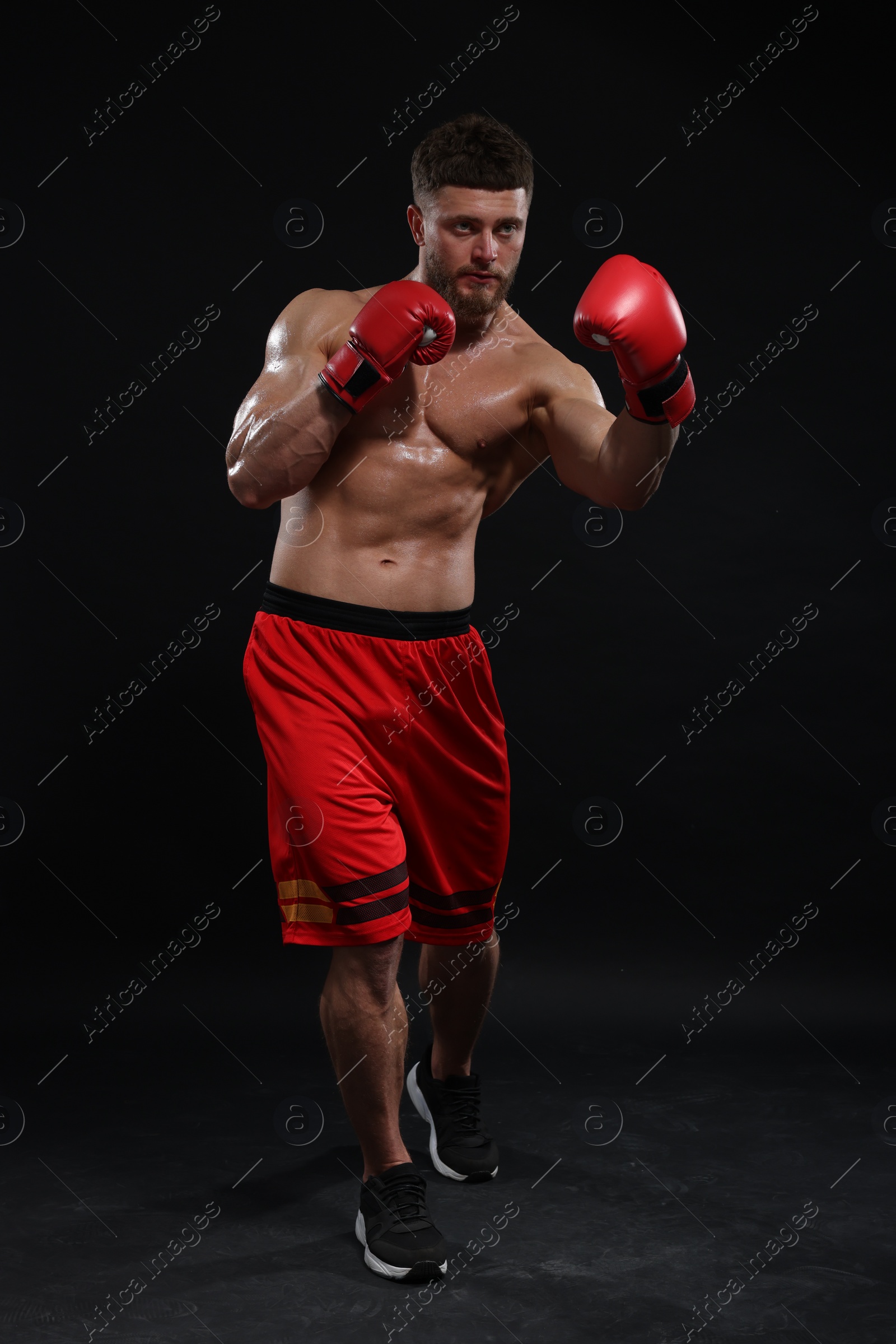 Photo of Man in boxing gloves fighting on black background