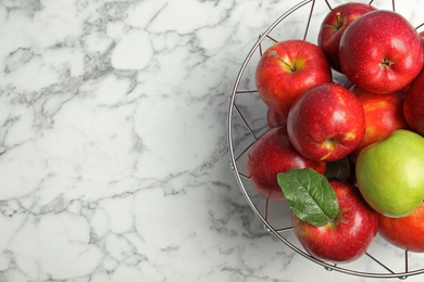 Green apple among red ones in metal basket and space for text on table, top view. Be different