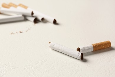 Broken cigarette on white textured table, closeup with space for text. No smoking concept
