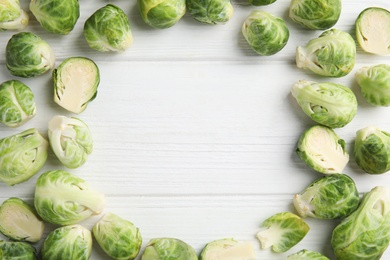 Frame made with fresh Brussels sprouts on white wooden table, flat lay. Space for text