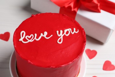 Photo of Bento cake with text Love You, gift box and paper hearts on white table, closeup. St. Valentine's day surprise