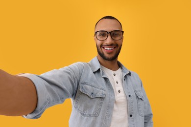 Photo of Smiling young man taking selfie on yellow background