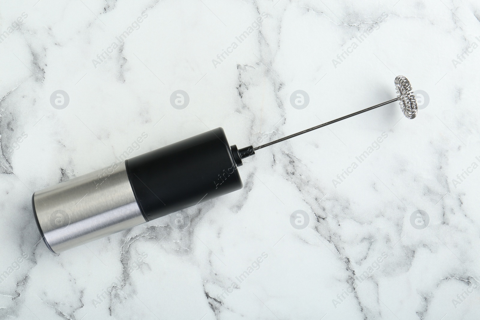 Photo of Black milk frother wand on white marble table, top view